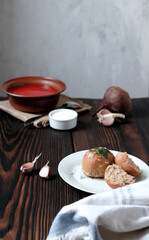 Garlic wholegrain donut and beetroot soup (borscht) with sour cream. Traditional ukrainian, russian soup on the wooden rustic table. Banner or menu recipe