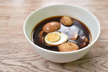 boiled half cut egg with tofu in herb brown soup on bowl