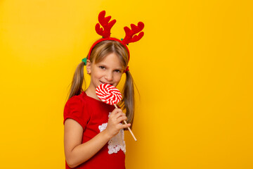Child wearing costume reindeer antlers eating lollipop