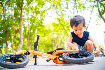 Little asian boy playing balance bike in city park