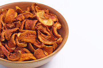 Pieces of dried apples in a wooden bowl on a white background
