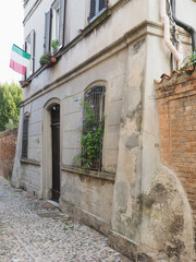 Fototapeta na wymiar Ferrara, Italy. Old house in the historic center with Italian flag.