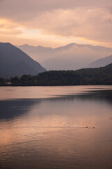 Avigliana, Italy. October 10th, 2020. Reflections of the autumn sunset on the lake of Avigliana with two swimming ducks. In the background, the Alps and Mount Pirchiriano.