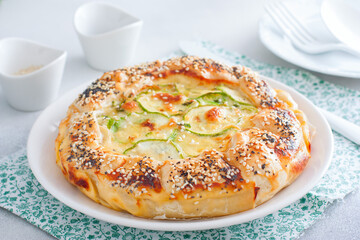 Open puff pastry zucchini pie sprinkled with poppy seeds and sesame seeds, selective focus
