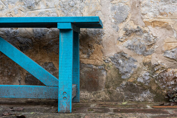 A blue bench in front of stone wall