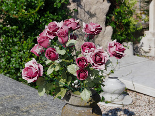 Ferrara, Italy. Certosa Monumental Cemetery. Vase with artificial flowers placed on a granite tomb.