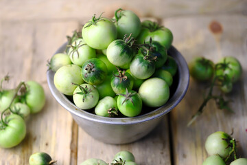 Selective focus. Green tomatoes in a bowl. Autumn tomato harvest.