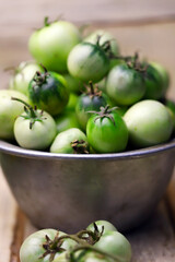 Selective focus. Green tomatoes in a bowl. Autumn tomato harvest.