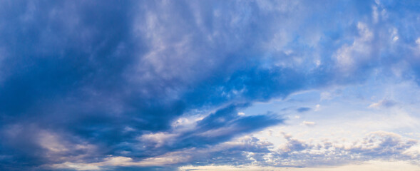 Dense clouds in blue low sky. Blue cold sky with heavy snow clouds in late autumn - panorama.