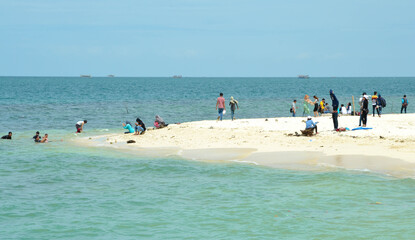 View of the beach and blue sky, white sand and tourists.
