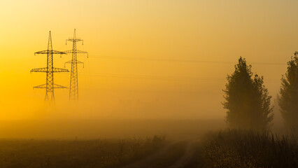 A foggy morning in an autumn field with a power line and a country road