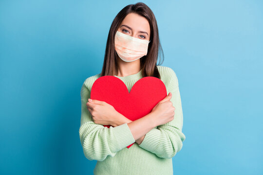 Photo of lovely young girl cuddle red paper heart figure wear orange face mask isolated blue color background