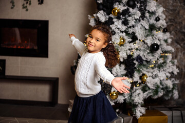 Christmas and New Year concept. Little curly hair baby girl standing with hands spread up.