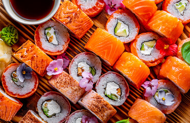 set of sushi roll with salmon, avocado, cream cheese, cucumber, rice, caviar, eel, tuna on wooden table
