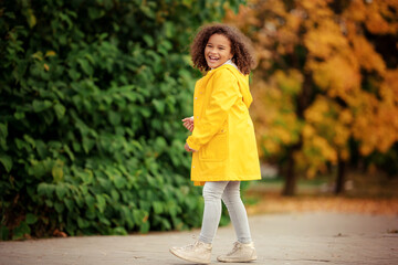 Cute afro girl smiling broadly outdoors and enjoying autumn day in park.