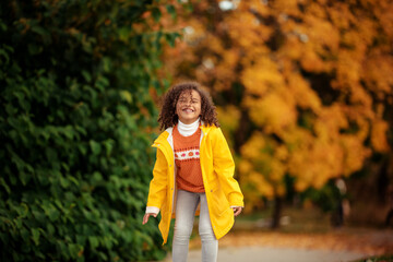 Cute afro girl smiling broadly outdoors and enjoying autumn day in park.