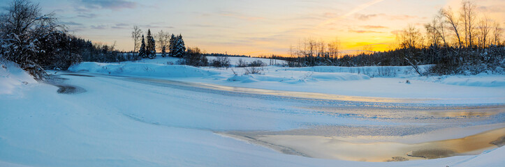 Fototapeta na wymiar Tranquil winter landscape with ice bound river at sunrise