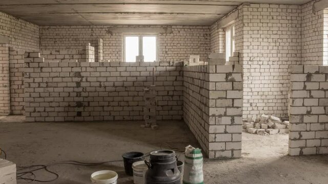 Builders laying brick walls inside appartment with professional tools timelapse. Workmen at work, bricklayers building wall, contractor and worker. Building materials around