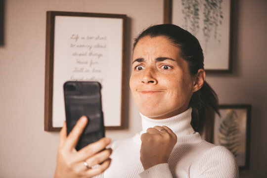 Angry Agitated Young Woman, Angry And Holding The Phone Waiting For A Call, Looking At The Smartphone, Depressed Sad Jealous Girl After A Fight Writes To The Guy On The Mobile Phone.