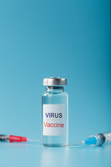 Syringes and ampoule with the vaccine against the Virus from diseases on a blue background.