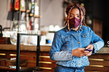 Stylish african american woman with dreadlocks afro hair, wear jeans jacket and face protect  mask...