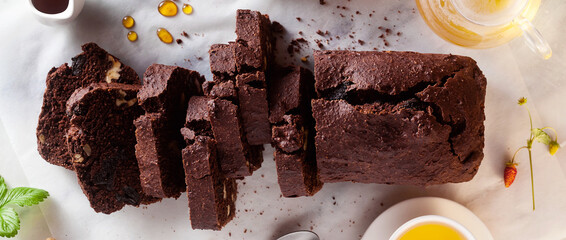banner of chocolate loaf cake with walnuts and prunes on the table with green tea. pause coffee