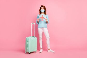 Full length view of girl holding in hands paper plane wear respiratory isolated over pink pastel color background