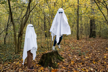 Ghost challenge in the forest or park. Two unrecognizable people teenagers disguised as ghosts with...