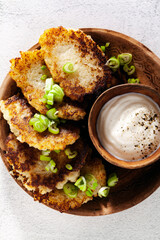 potato pancakes with yogurt and green onions and black pepper. in clay pots on a white background