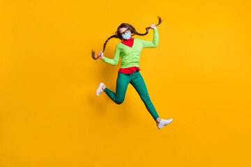 Plakat Full length body size view of funky cheerful girl jumping running holding pigtails wear mask isolated bright yellow color background