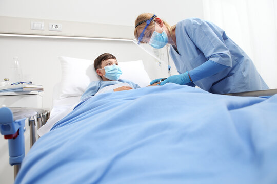 Nurse Takes Care Of The Child Patient In The Hospital Bed, Putting On The Oxygen Mask, Corona Virus Covid 19 Protection Concept 