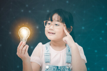 Asian Little girl holding light bulb in the black background, ideas with innovative technology and Electricity, education and people concept
