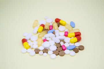 A bunch of colorful pills on the pale yellow background
