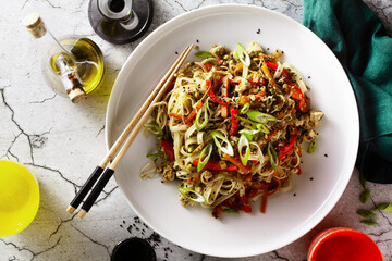 vegan pad thai rice pasta with vegetables and tofu on gray concrete background with soy sauce and...