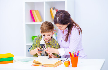 Mom and baby are looking through a microscope together at home at home. Home education