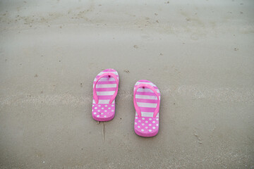 Pink sandal slipper shoes walking stpe on the beach seashore coastline for comfortable vacation holidays relaxation concept