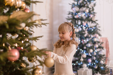 Little girl spends time decorating the Christmas tree. Preparing for the holidays. Santa will be glad