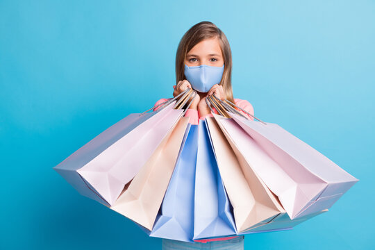 Photo portrait of girl holding shopping bags wear facial safe mask isolated on pastel blue colored background