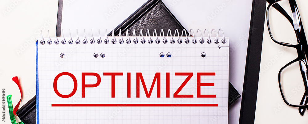 Poster the word optimize is written in red in a white notebook next to black-framed glasses.