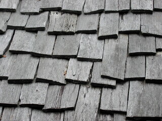 Weathered wooden roof composed of overlapping wooden boards. Rough and uniform texture.