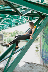 Woman resting between the iron beams of a bridge.