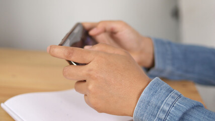 Close up of adult person hands holding and using smart phone to play online game
