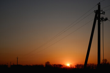 High voltage electric pylon and electrical wire with sunset sky.