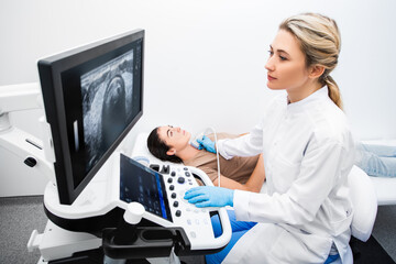 Woman endocrinologist making ultrasonography to a female patient in an ultrasound office....