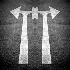 bright twin white direction arrow on a new black clean asphalt road surface creating patterns and designs