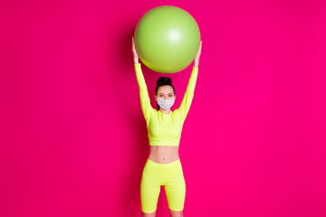 Photo of positive young sportswoman raise fit ball up wear medical mask isolated pink shine color background