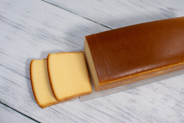 Homemade sliced butter cake on white wooden background.