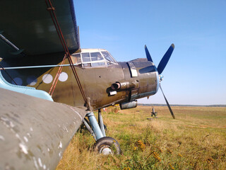 Old green biplane with a piston engine with a propeller on the tarmac on a Sunny day in autumn