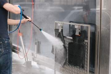 Car washing. Cleaning car using high pressure water. Man washing his car outdoor