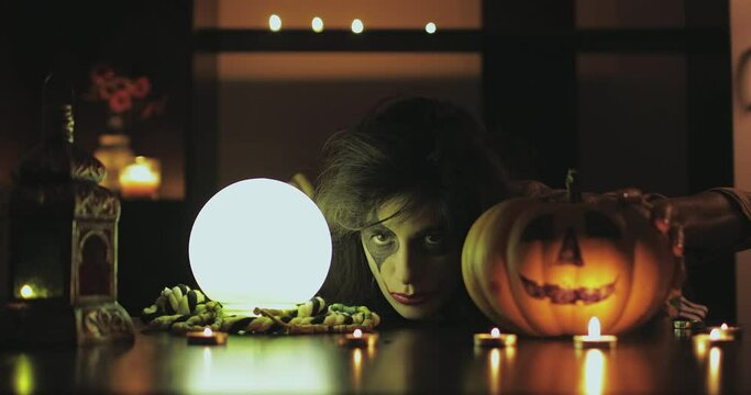 Female with scary halloween mask with pumpkin and crystal magic ball. 